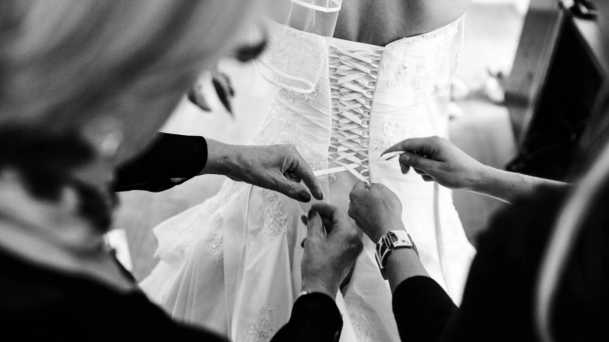 getting ready der braut bei einer hochzeit. das kleid wird geschnürt.